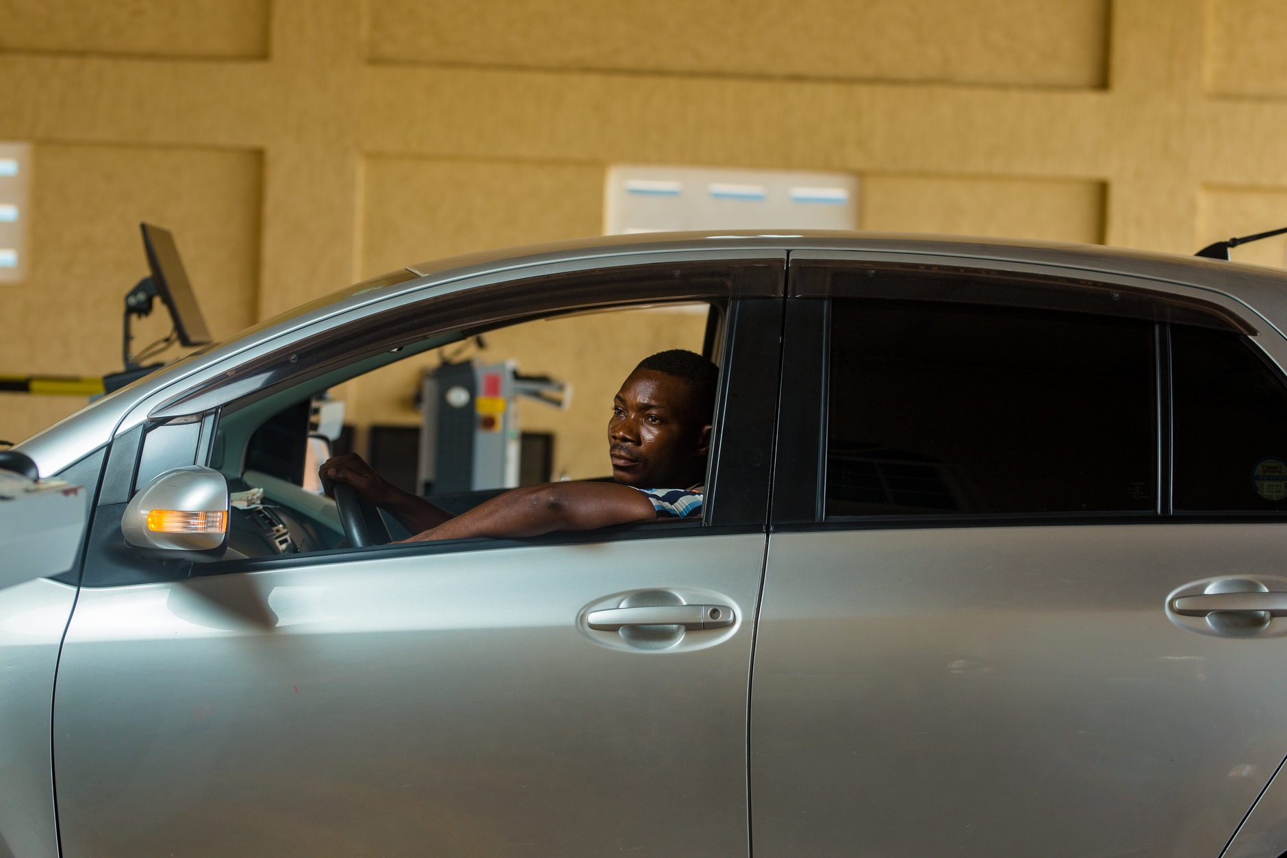A person sitting in the driver's seat of a car being checked over before a test