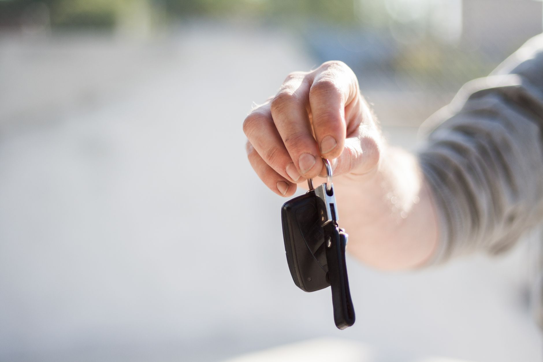 A set of car keys being handed over to a new driver
