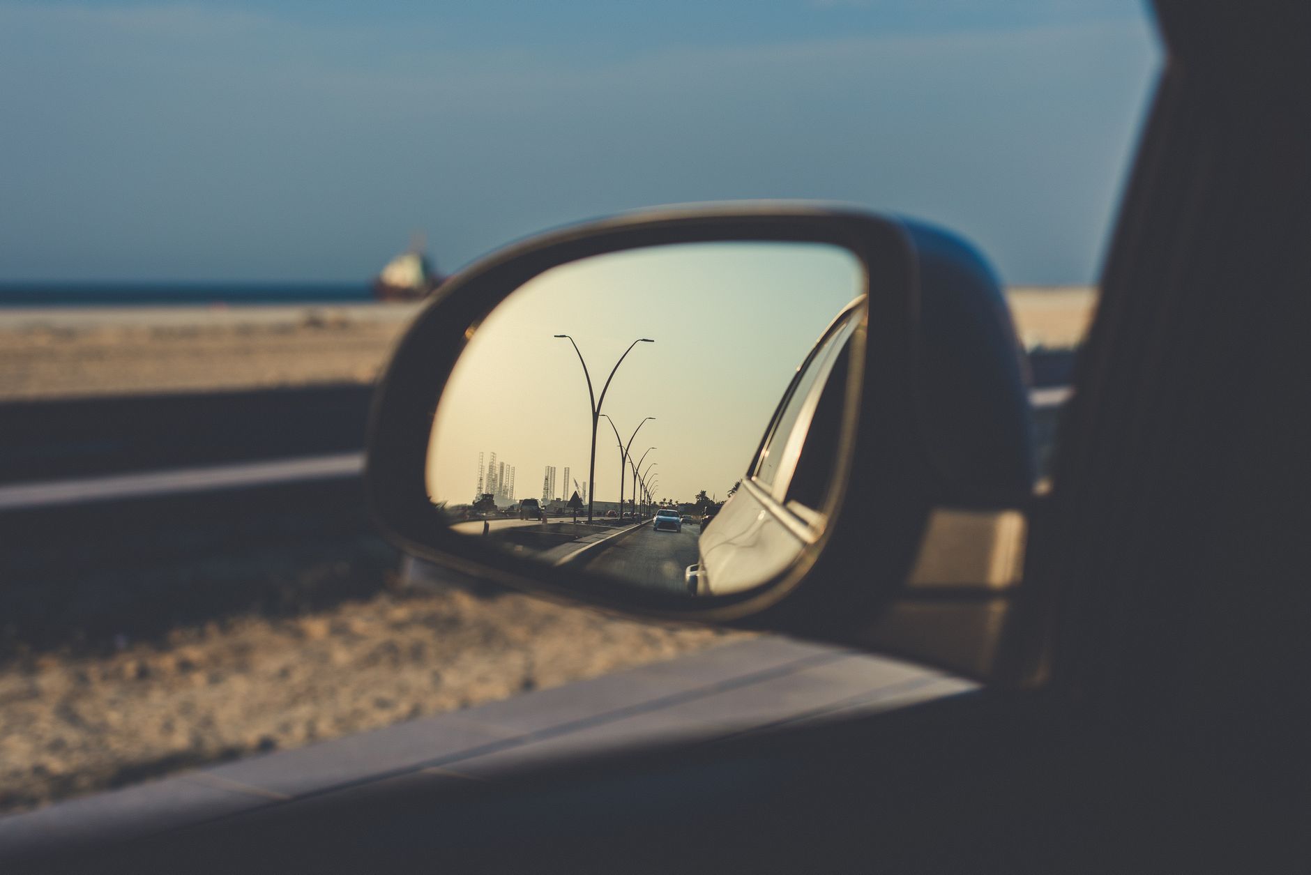 A car side mirror reflecting the road behind