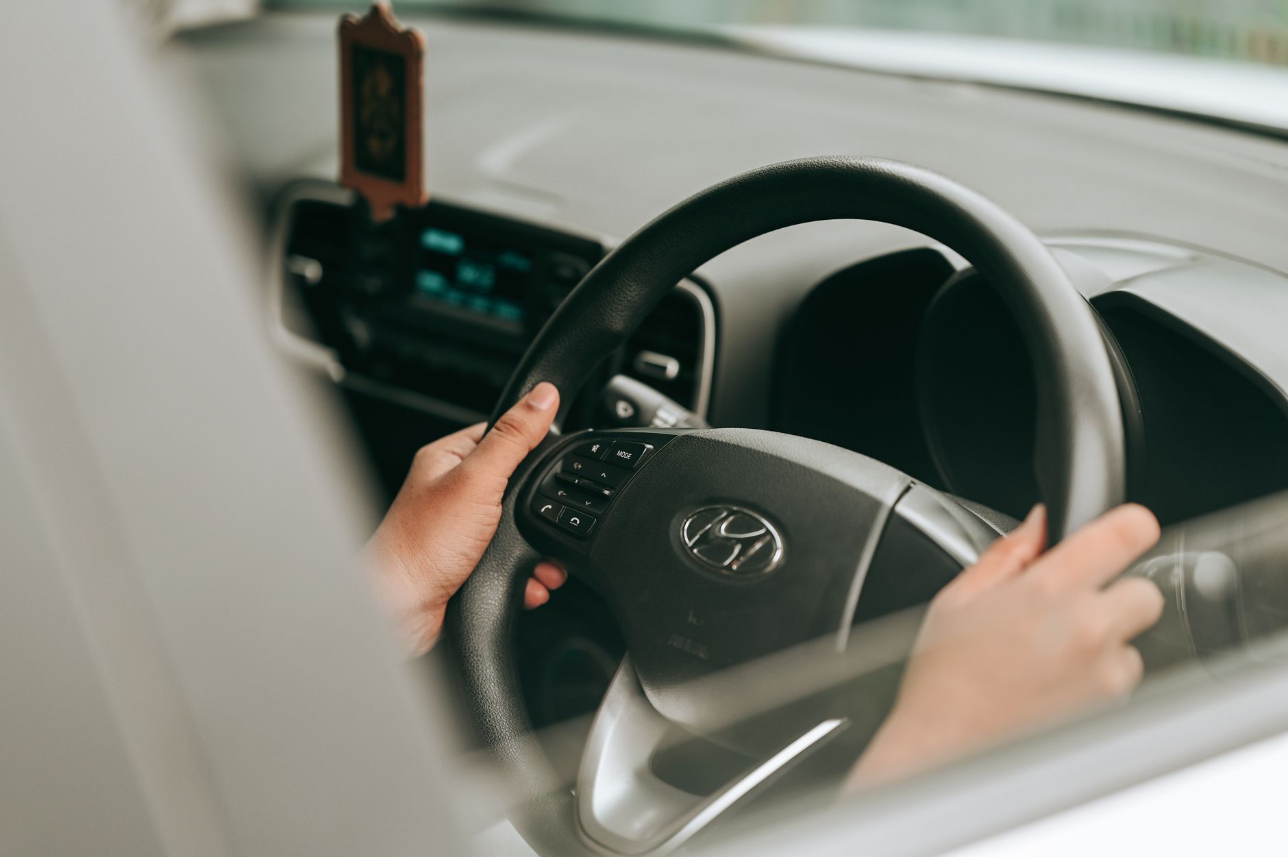 A learner's hands resting steadily on a car steering wheel, ready to move off