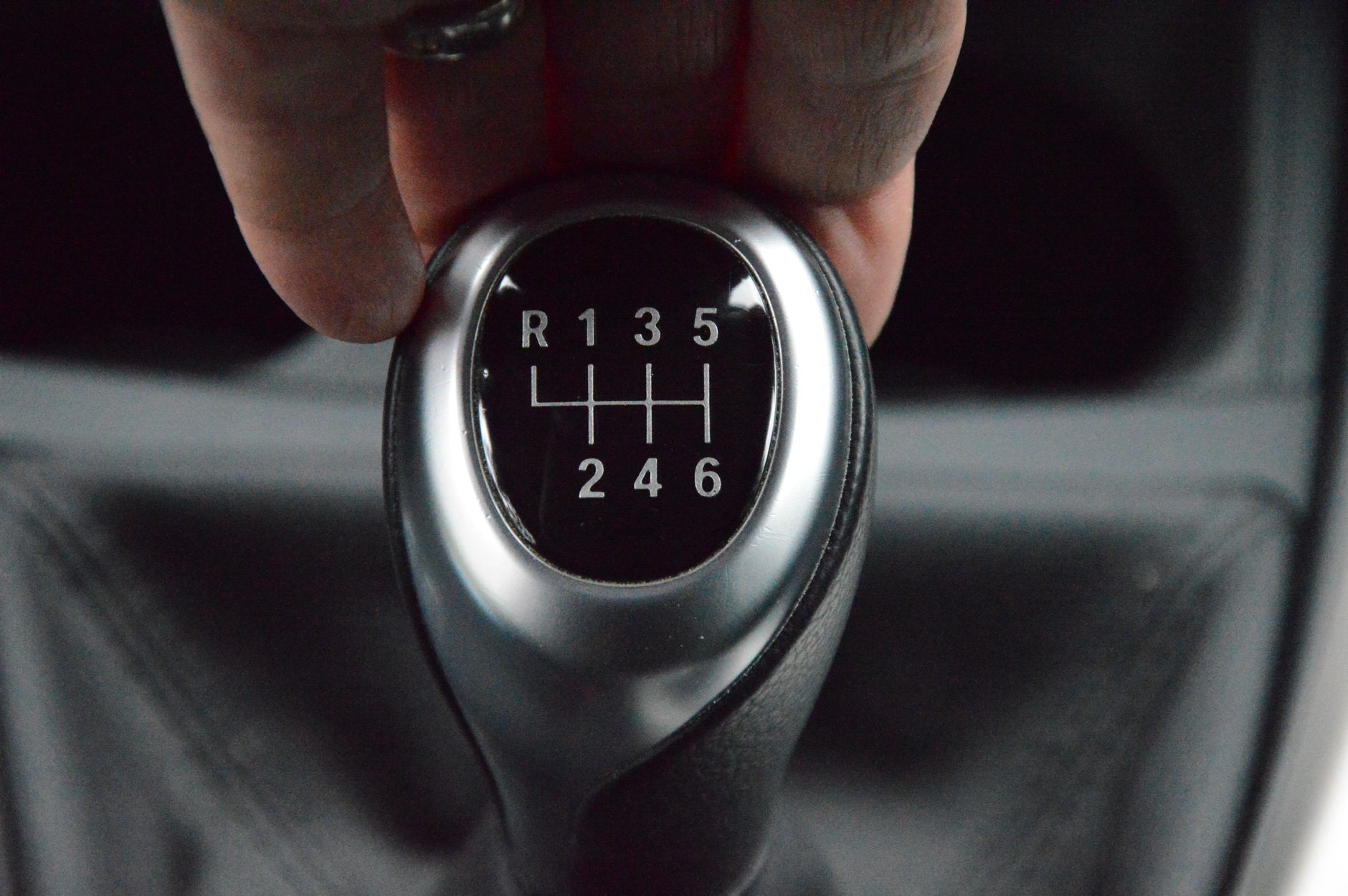 A hand resting on a manual gear stick inside a car
